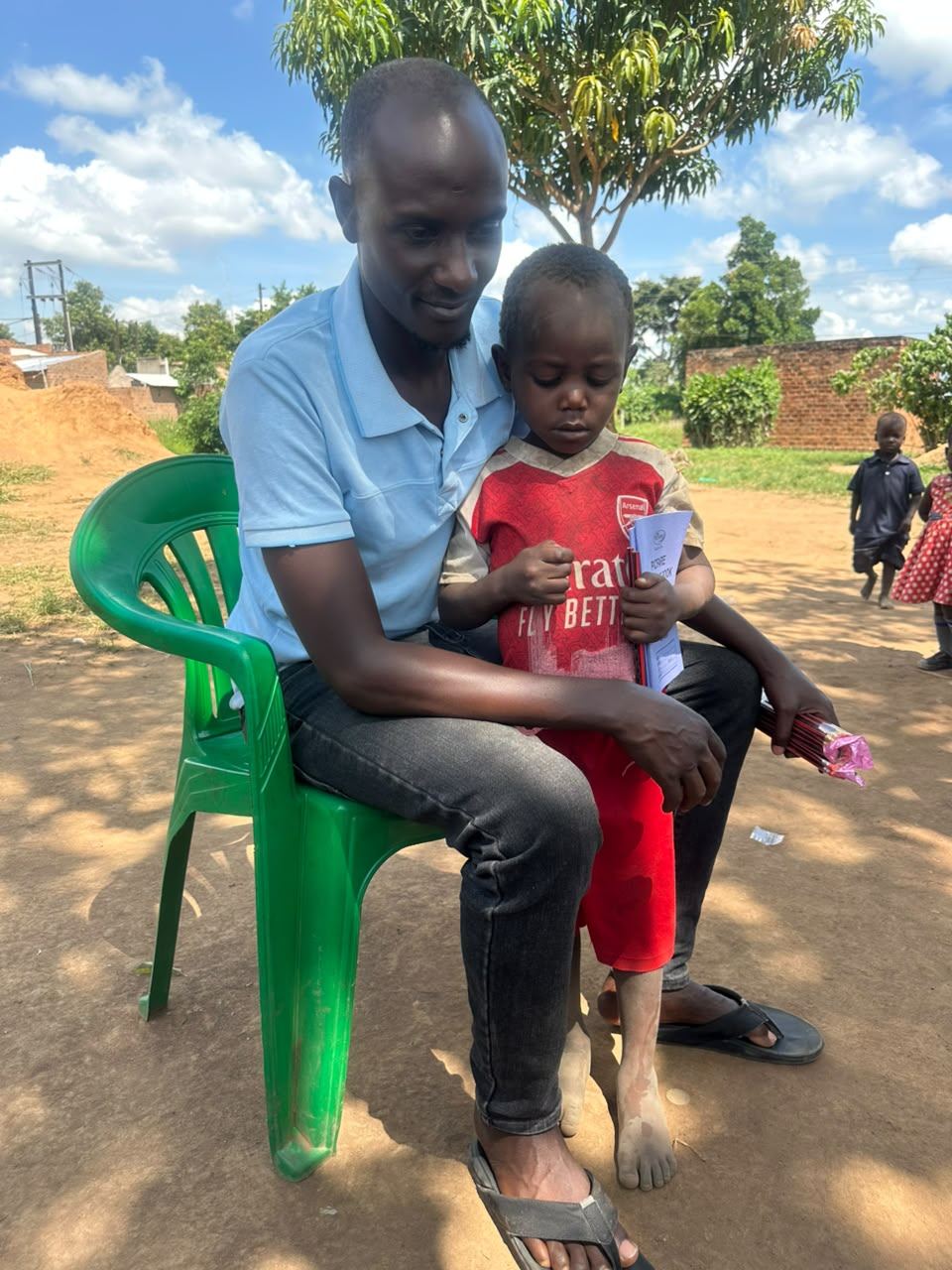 A team member sits with a young boy in a red shirt, his arm around him