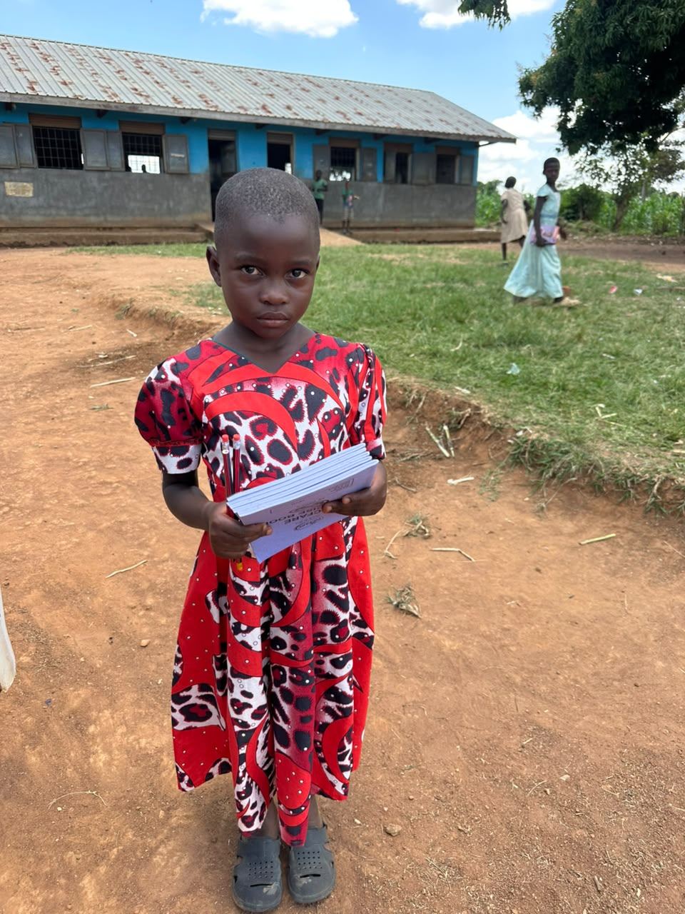 A young girl holds her new book outside her school