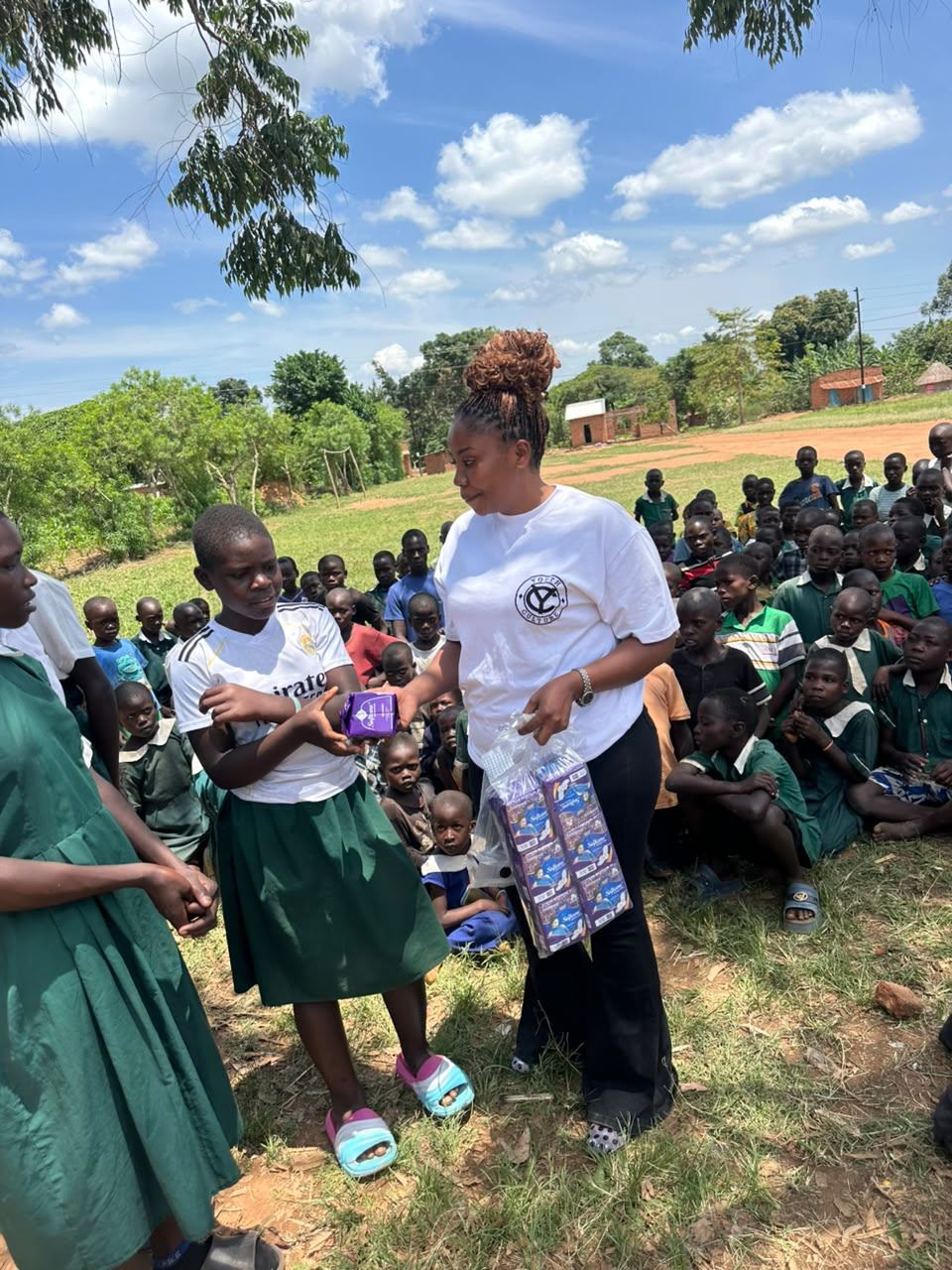 A volunteer hands scholastic materials to a pupil